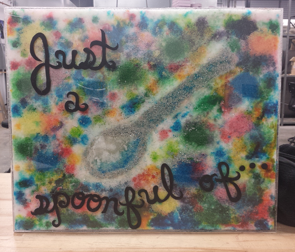 "Just a Spoonful" dyed sugar arranged inside a sealed plexiglass encasement.